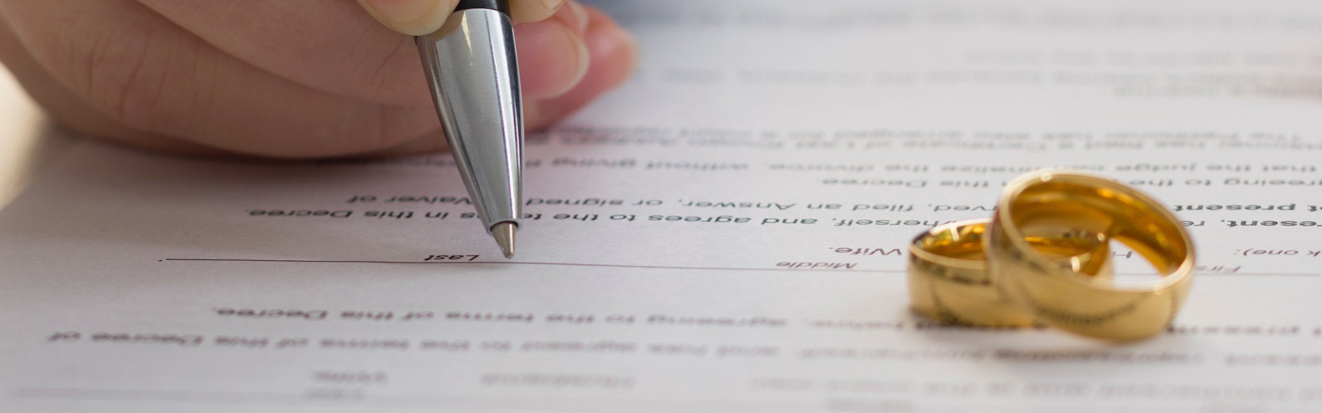 wedding rings on kept on paper while a persons is writing on paper